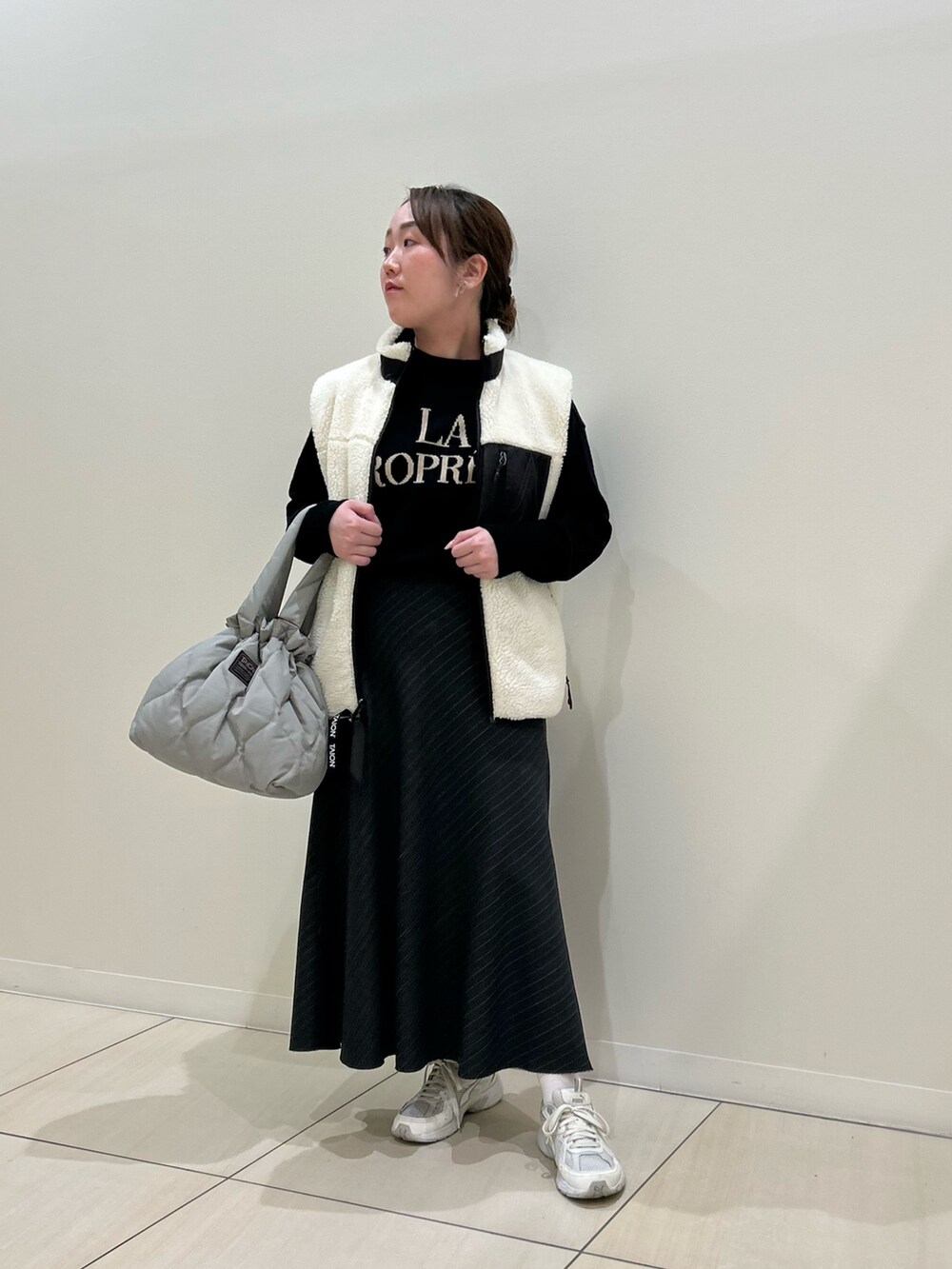 ホワイト系のダウンベスト、ブラック系のカーディガン/ボレロ、グリーン系のトートバッグを着用したレディースの冬コーディネートの7枚目の写真