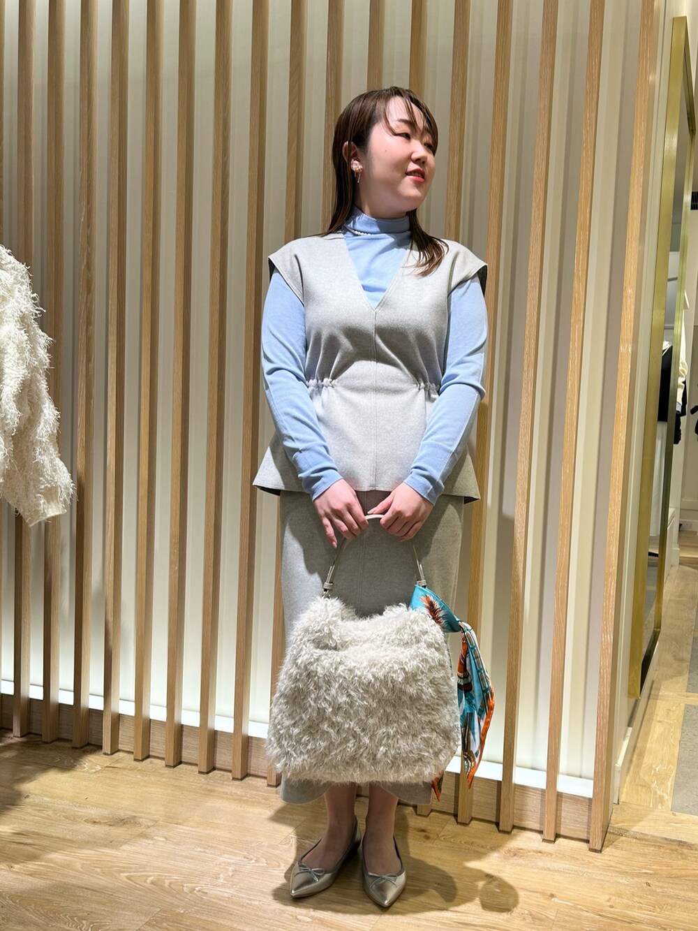 グレー系のベスト、グレー系のスカート、ブルー系のニット/セーターを着用したレディースの冬コーディネートの7枚目の写真