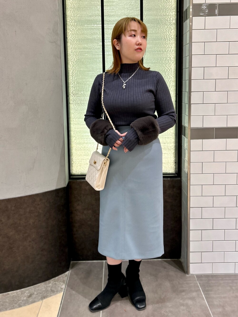 グレー系のニット/セーター、ブルー系のスカート、ホワイト系のショルダーバッグを着用したレディースの冬コーディネートの8枚目の写真