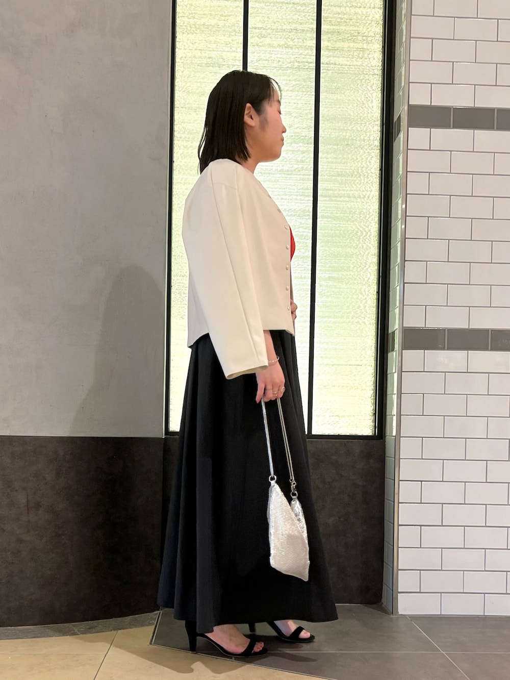 ベージュ系のブルゾン、レッド系のTシャツ/カットソー、ブラック系のスカートを着用したレディースの秋コーディネートの3枚目の写真