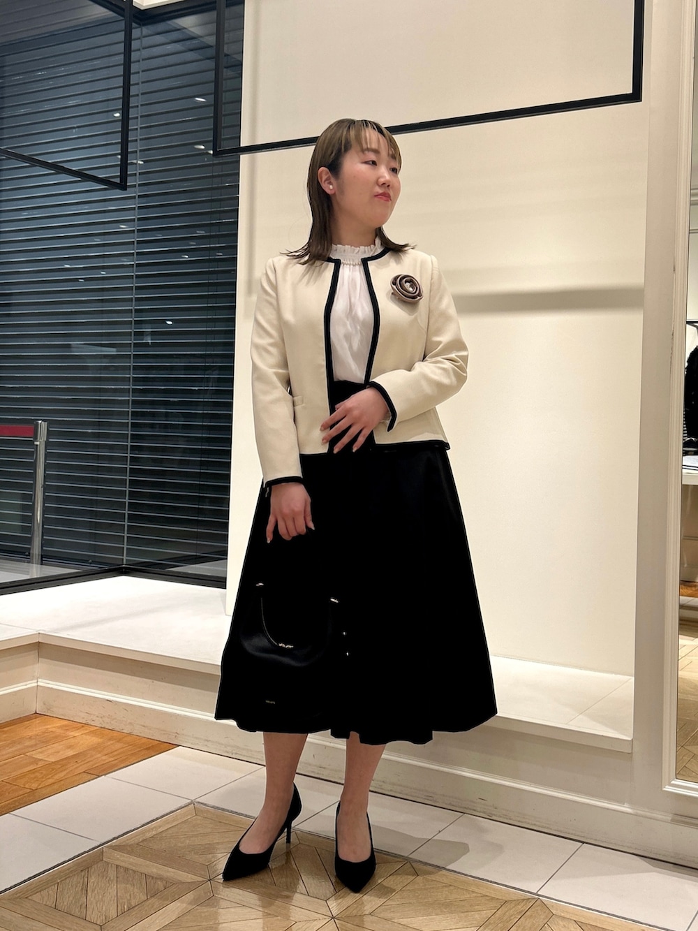 ホワイト系のノーカラージャケット、ホワイト系のシャツ/ブラウス、ブラック系のショルダーバッグを着用したレディースの冬コーディネートの2枚目の写真