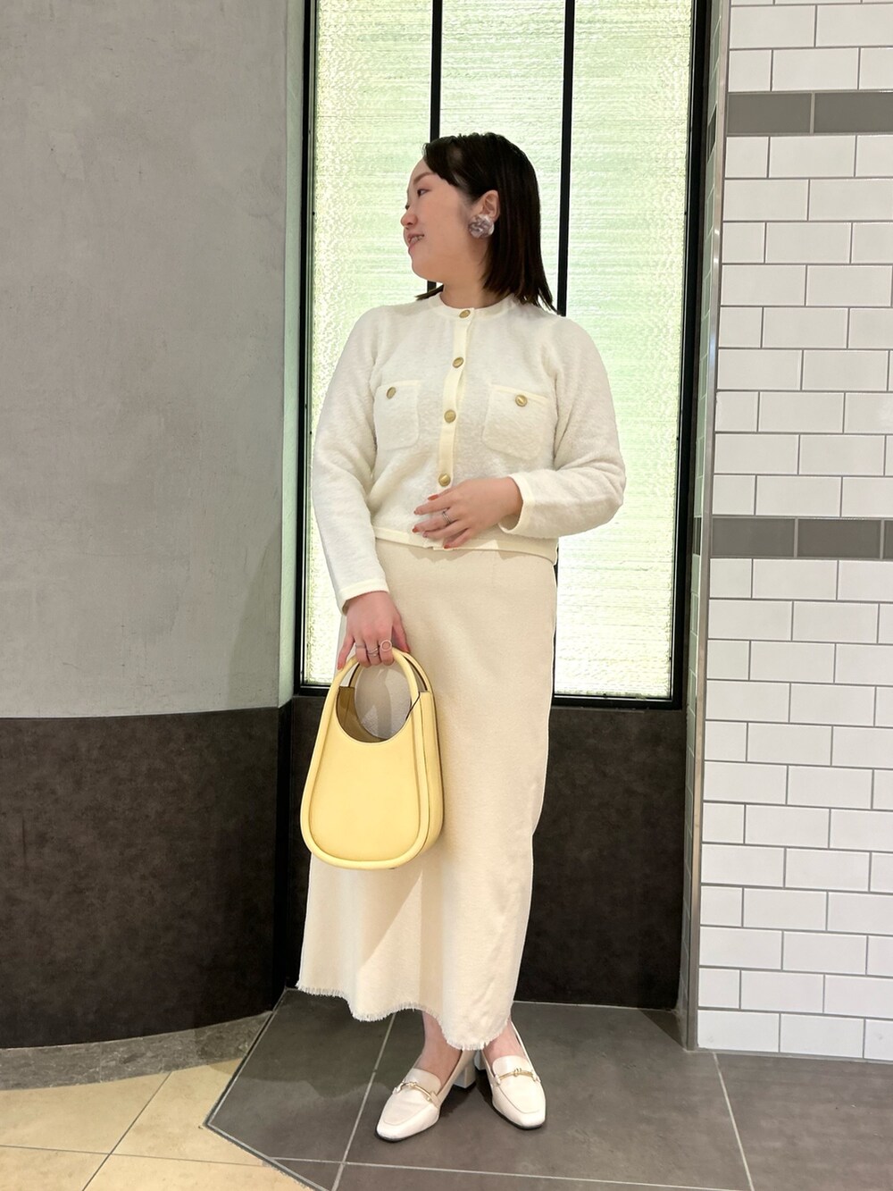 ホワイト系のカーディガン/ボレロ、ホワイト系のスカート、イエロー系のハンドバッグを着用したレディースの秋コーディネートの6枚目の写真