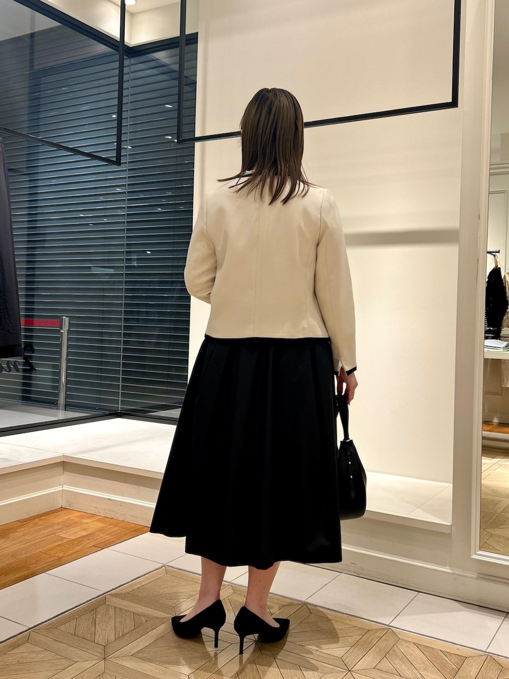 ホワイト系のノーカラージャケット、ホワイト系のシャツ/ブラウス、ブラック系のショルダーバッグを着用したレディースの冬コーディネートの4枚目の写真