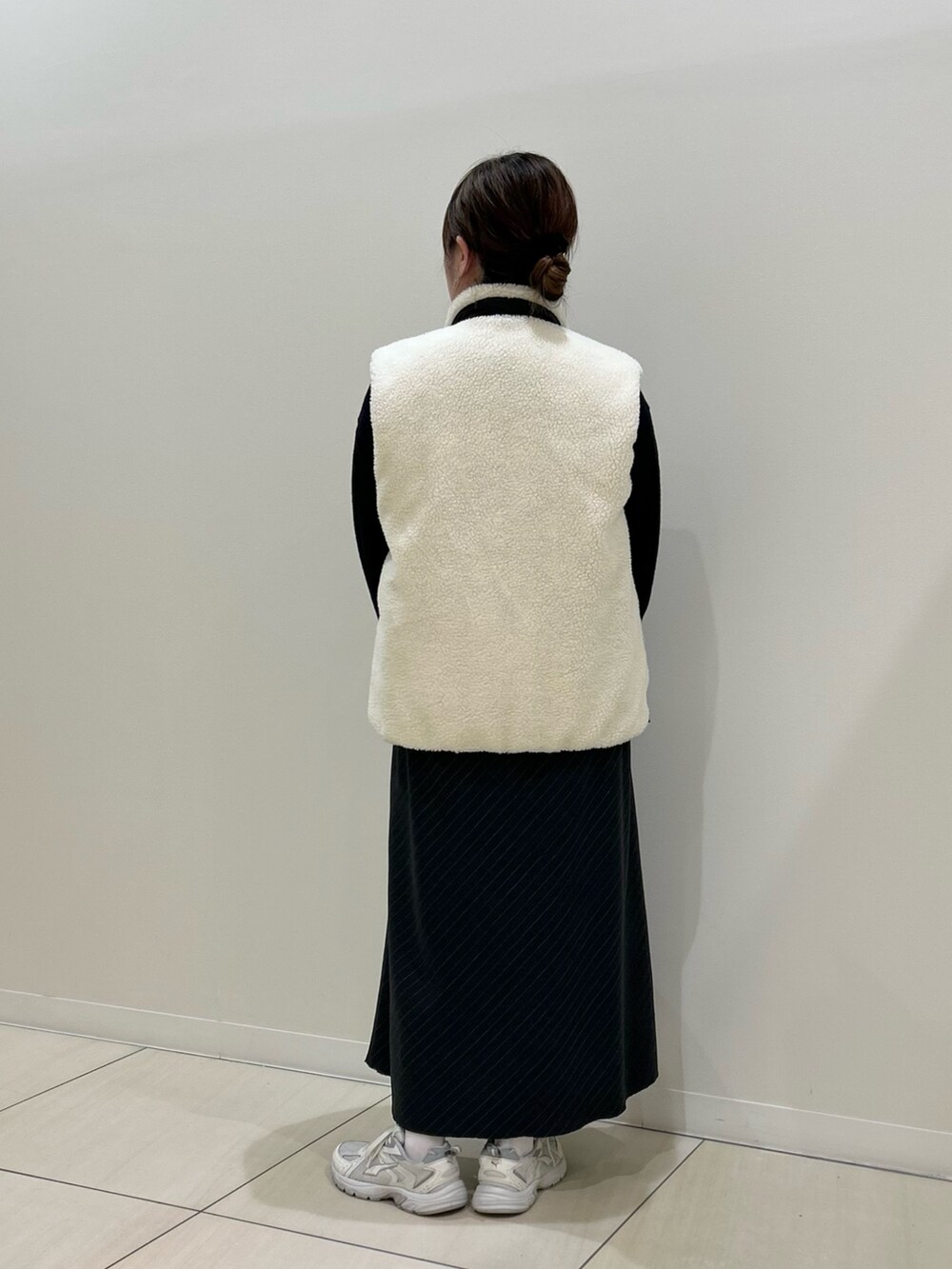 ホワイト系のダウンベスト、ブラック系のカーディガン/ボレロ、グリーン系のトートバッグを着用したレディースの冬コーディネートの3枚目の写真