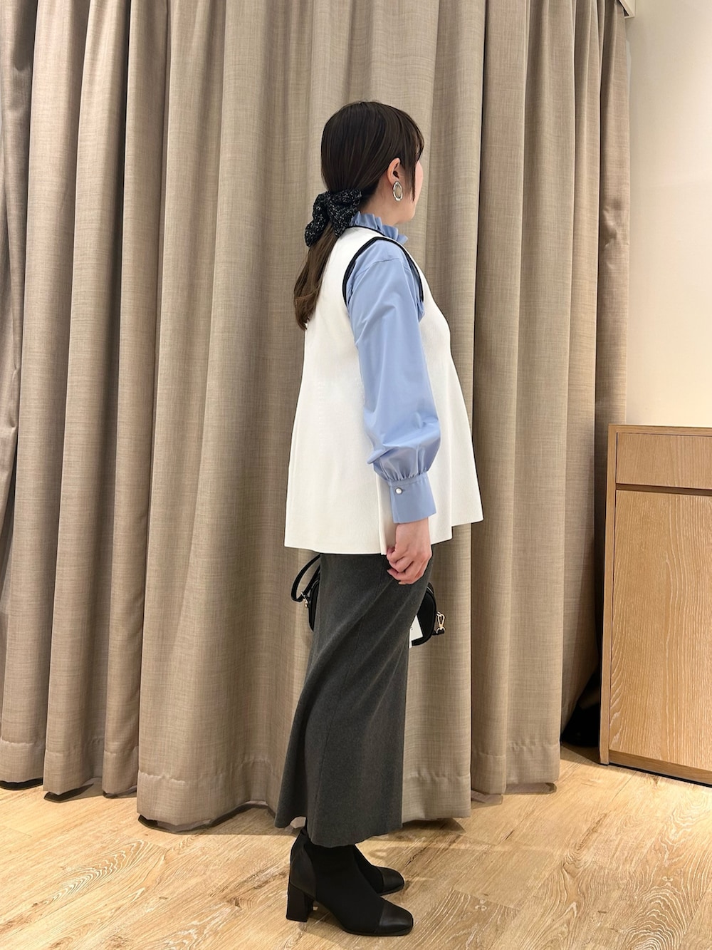 ホワイト系のベスト、ブルー系のシャツ/ブラウス、グレー系のスカートを着用したレディースの冬コーディネートの4枚目の写真