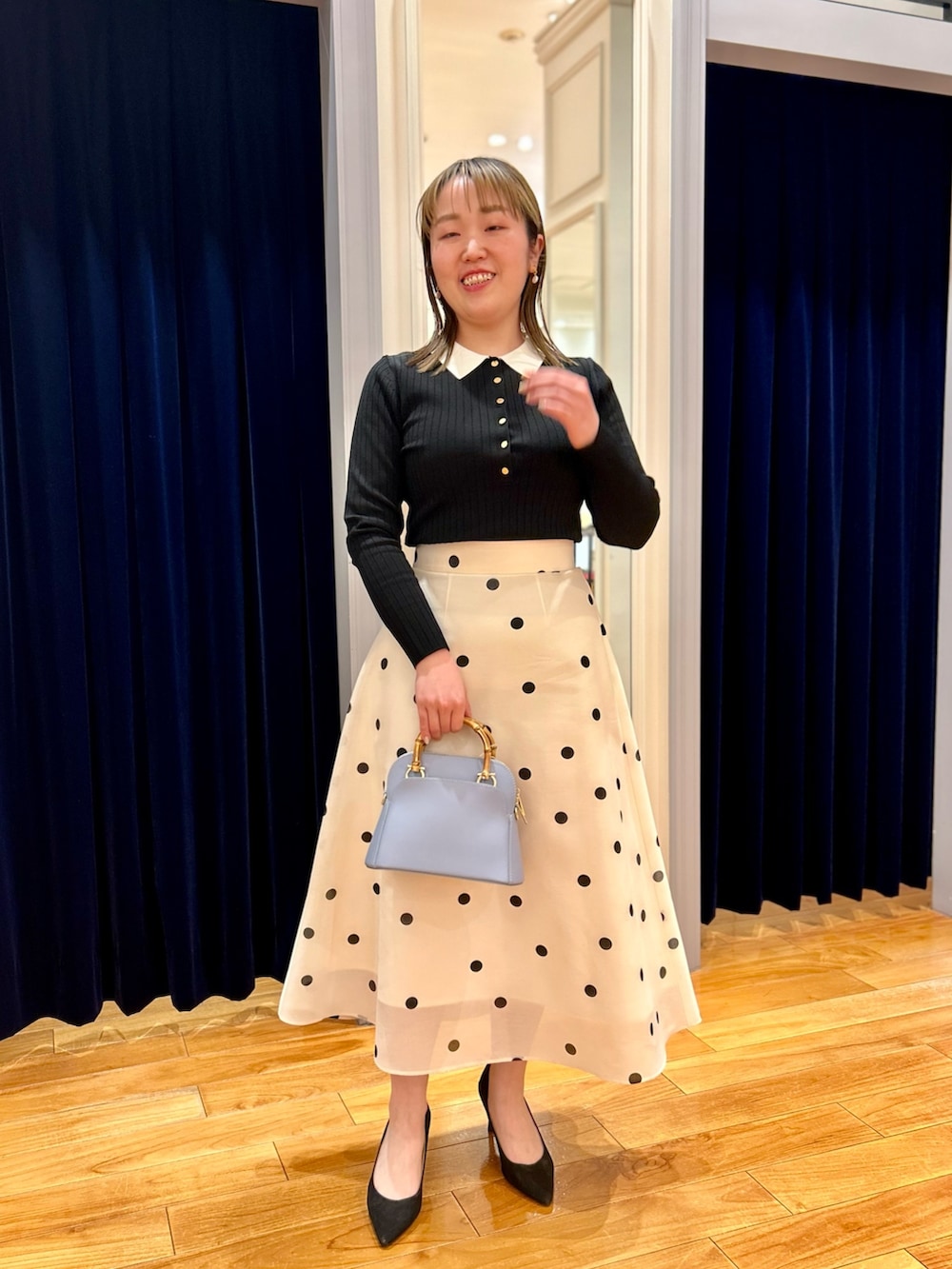 ブラック系のニット/セーター、ホワイト系のスカート、ブルー系のショルダーバッグを着用したレディースの冬コーディネートの6枚目の写真
