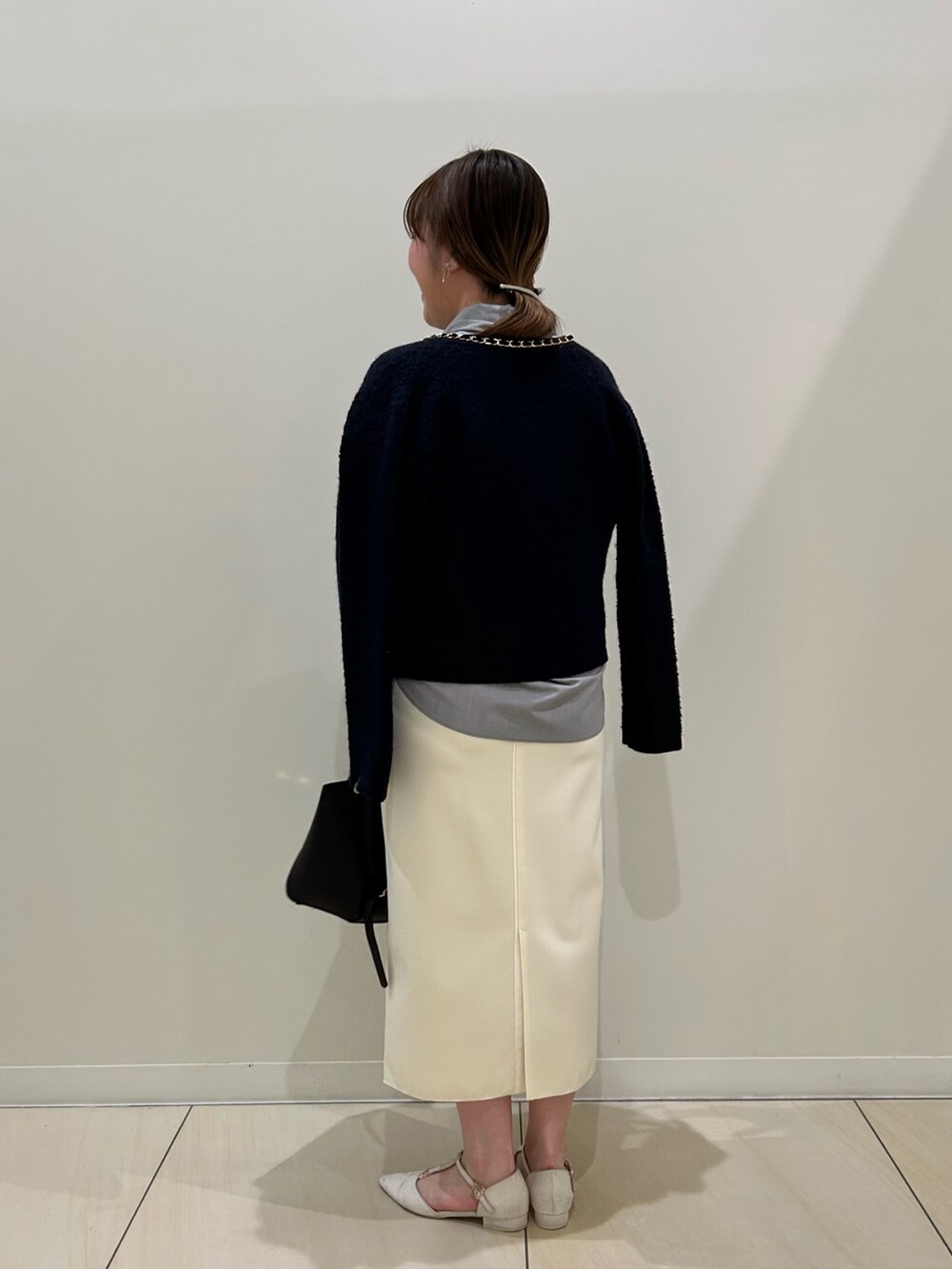 ブルー系のカーディガン/ボレロ、グレー系のシャツ/ブラウス、ホワイト系のスカートを着用したレディースの秋コーディネートの3枚目の写真