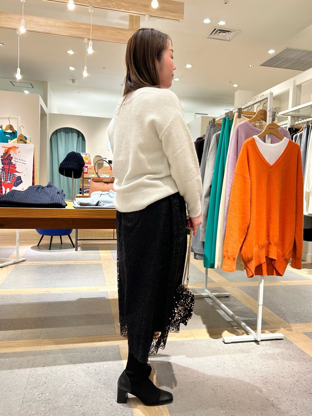 ホワイト系のニット/セーター、ブラック系のスカート、その他のショルダーバッグを着用したレディースの冬コーディネートの2枚目の写真