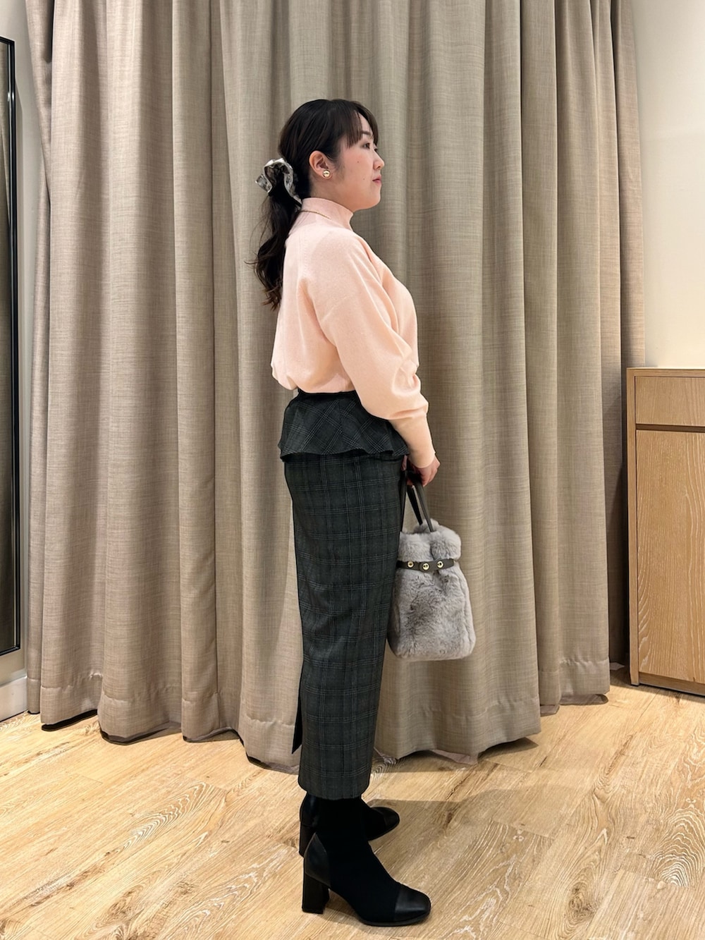 ピンク系のニット/セーター、ブラック系のスカート、ベージュ系のトートバッグを着用したレディースの冬コーディネートの4枚目の写真