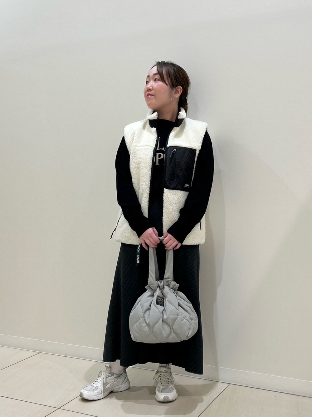 ホワイト系のダウンベスト、ブラック系のカーディガン/ボレロ、グリーン系のトートバッグを着用したレディースの冬コーディネートの5枚目の写真