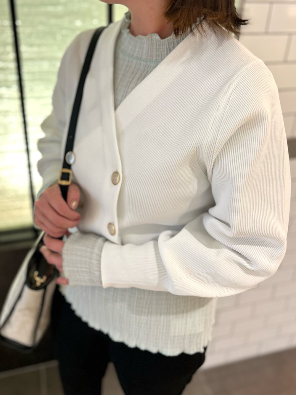 ホワイト系のカーディガン/ボレロ、グリーン系のTシャツ/カットソー、ブラック系のトートバッグを着用したレディースの春コーディネートの7枚目の写真