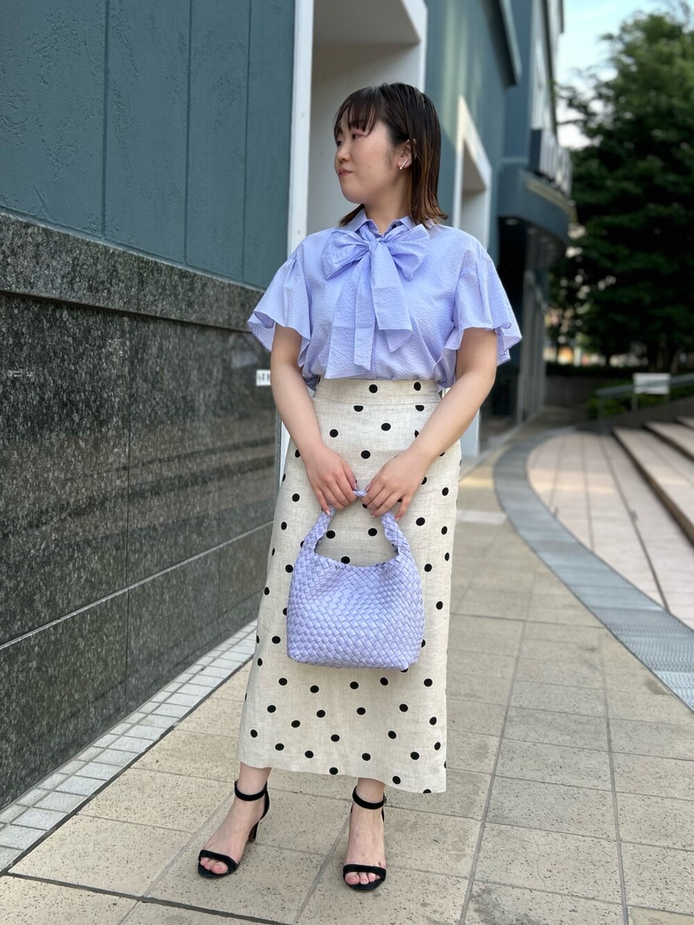 パープル系のシャツ/ブラウス、ベージュ系のスカート、パープル系のショルダーバッグを着用したレディースの春コーディネートの9枚目の写真