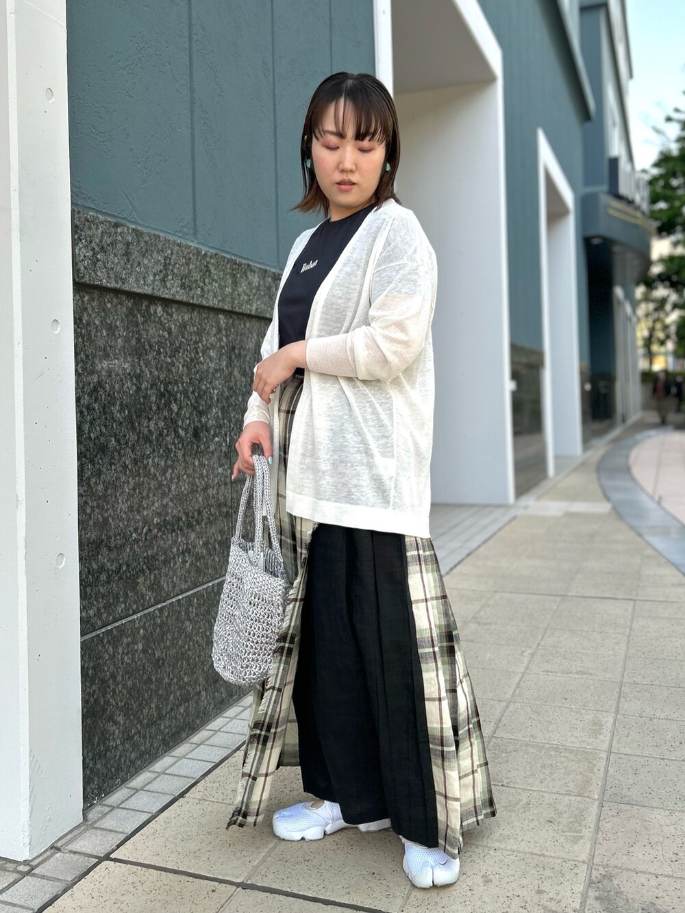 ホワイト系のカーディガン/ボレロ、ブラック系のスカート、シルバー系のバックパック/リュックを着用したレディースの春コーディネートの2枚目の写真