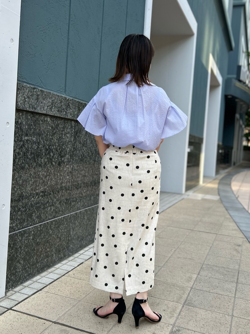 パープル系のシャツ/ブラウス、ベージュ系のスカート、パープル系のショルダーバッグを着用したレディースの春コーディネートの4枚目の写真