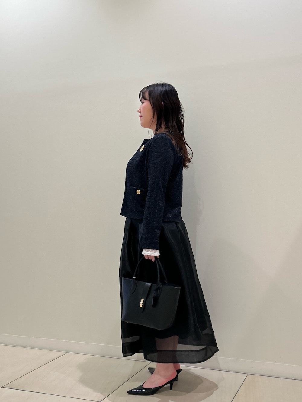 ブルー系のノーカラージャケット、ブラック系のスカート、ホワイト系のTシャツ/カットソーを着用したレディースの春コーディネートの2枚目の写真