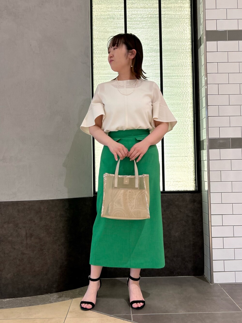 ベージュ系のトートバッグ、ホワイト系のシャツ/ブラウス、グリーン系のスカートを着用したレディースの春コーディネートの8枚目の写真