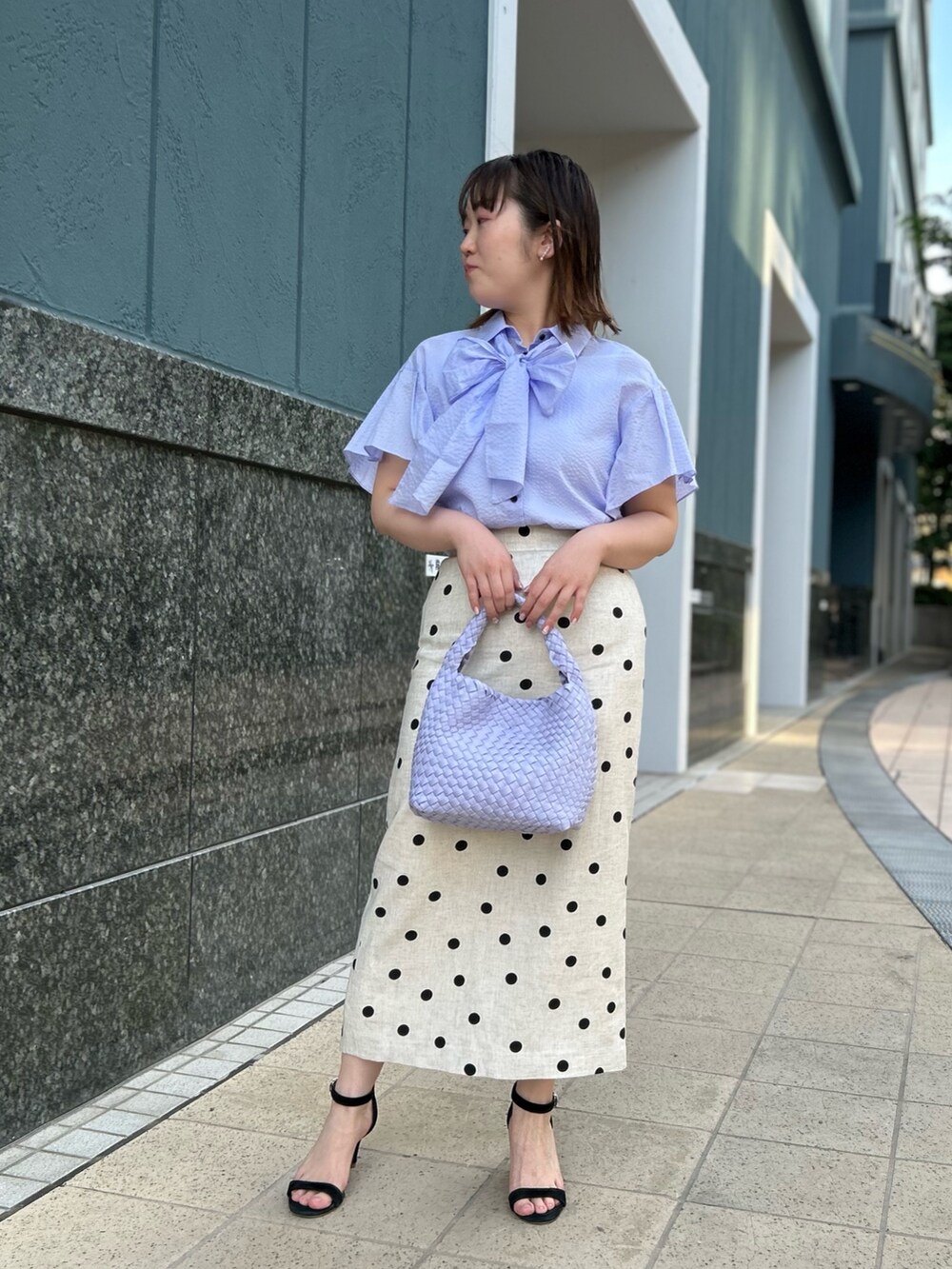 パープル系のシャツ/ブラウス、ベージュ系のスカート、パープル系のショルダーバッグを着用したレディースの春コーディネートの6枚目の写真