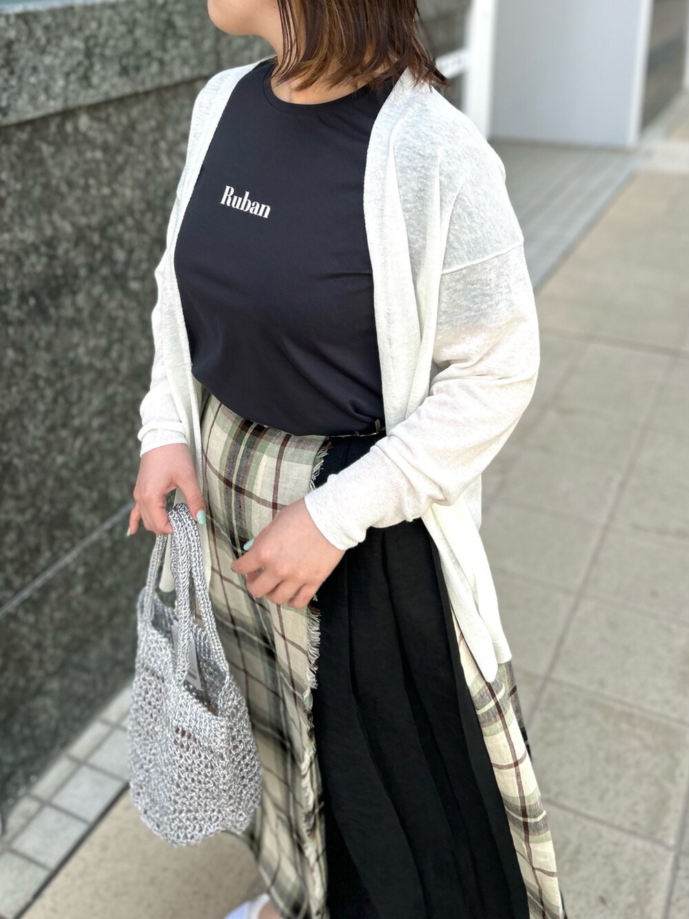 ホワイト系のカーディガン/ボレロ、ブラック系のスカート、シルバー系のバックパック/リュックを着用したレディースの春コーディネートの7枚目の写真