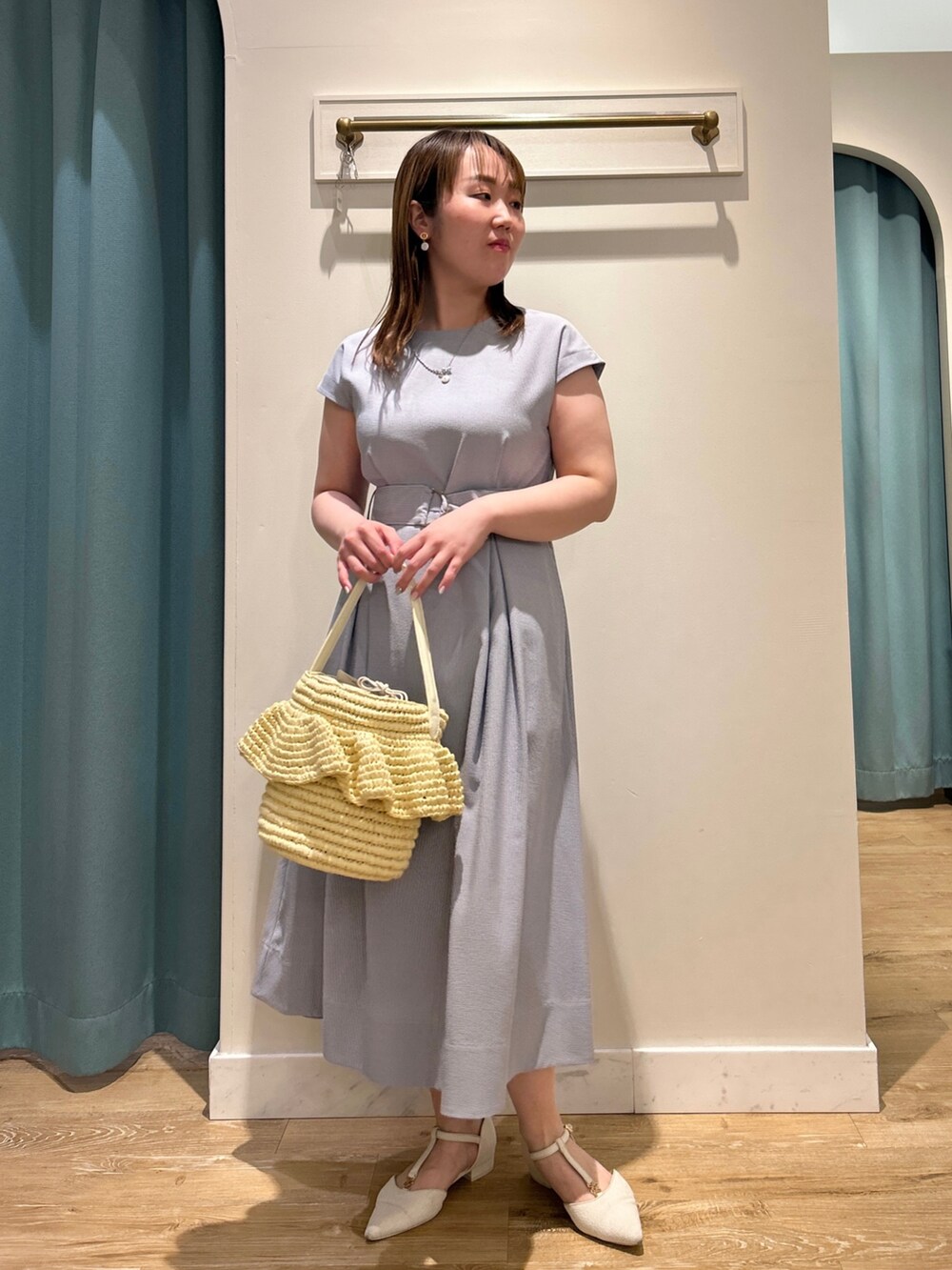 ブルー系のワンピース、ベージュ系のかごバッグ、シルバー系のネックレスを着用したレディースの夏コーディネートの2枚目の写真