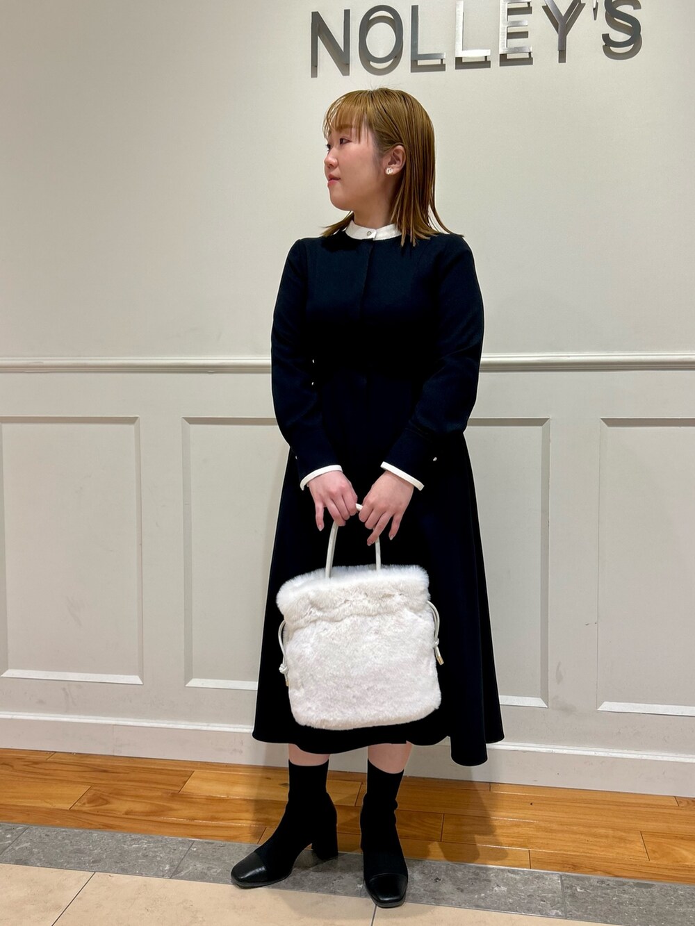 ブルー系のワンピース、ホワイト系のショルダーバッグ、ホワイト系のイヤリングを着用したレディースの冬コーディネートの2枚目の写真