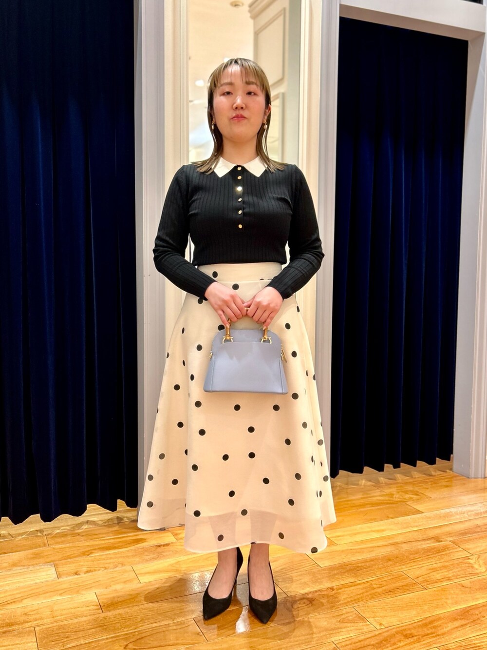 ブラック系のニット/セーター、ホワイト系のスカート、ブルー系のショルダーバッグを着用したレディースの冬コーディネートの2枚目の写真