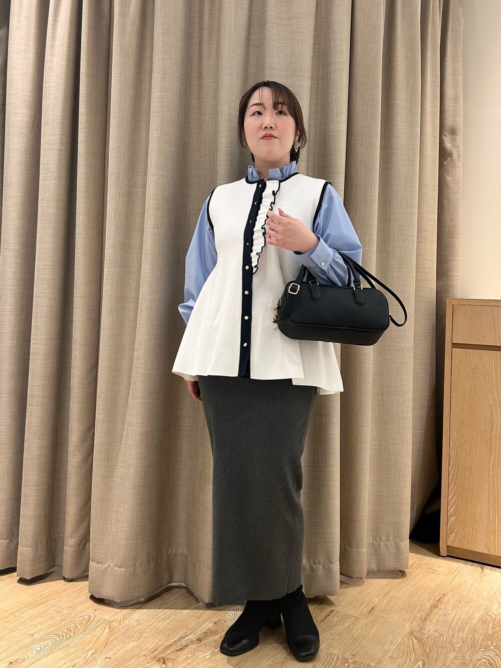 ホワイト系のベスト、ブルー系のシャツ/ブラウス、グレー系のスカートを着用したレディースの冬コーディネートの10枚目の写真