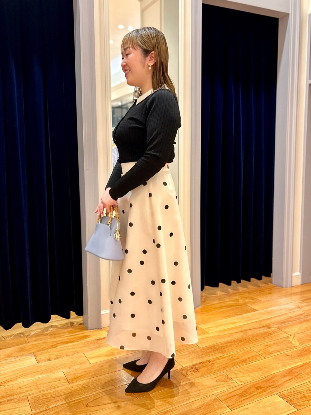 ブラック系のニット/セーター、ホワイト系のスカート、ブルー系のショルダーバッグを着用したレディースの冬コーディネートの3枚目の写真