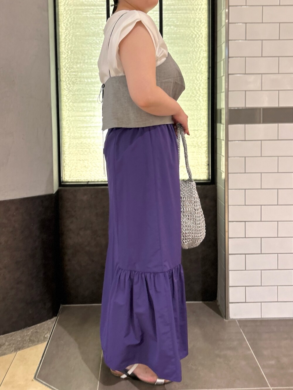グレー系のTシャツ/カットソー、パープル系のスカート、シルバー系のバックパック/リュックを着用したレディースの夏コーディネートの2枚目の写真