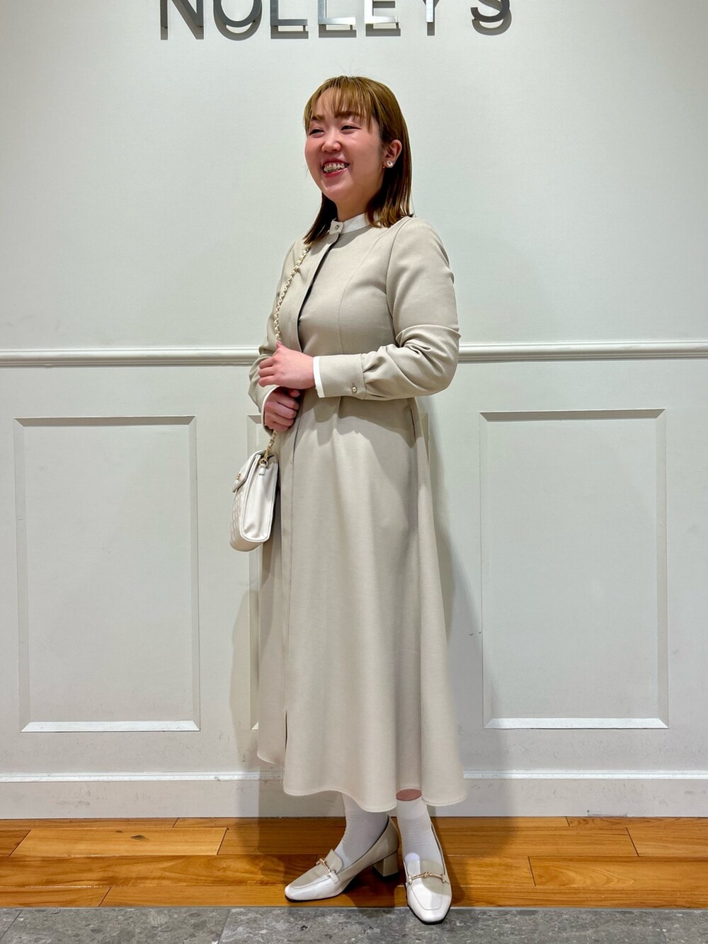 ベージュ系のワンピース、ホワイト系のショルダーバッグ、ホワイト系のイヤリングを着用したレディースの冬コーディネートの9枚目の写真