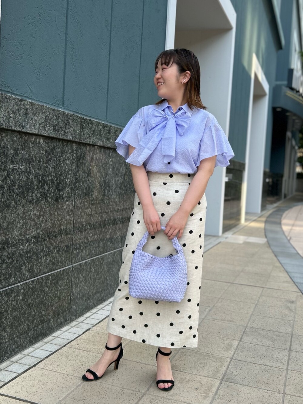 パープル系のシャツ/ブラウス、ベージュ系のスカート、パープル系のショルダーバッグを着用したレディースの春コーディネートの5枚目の写真