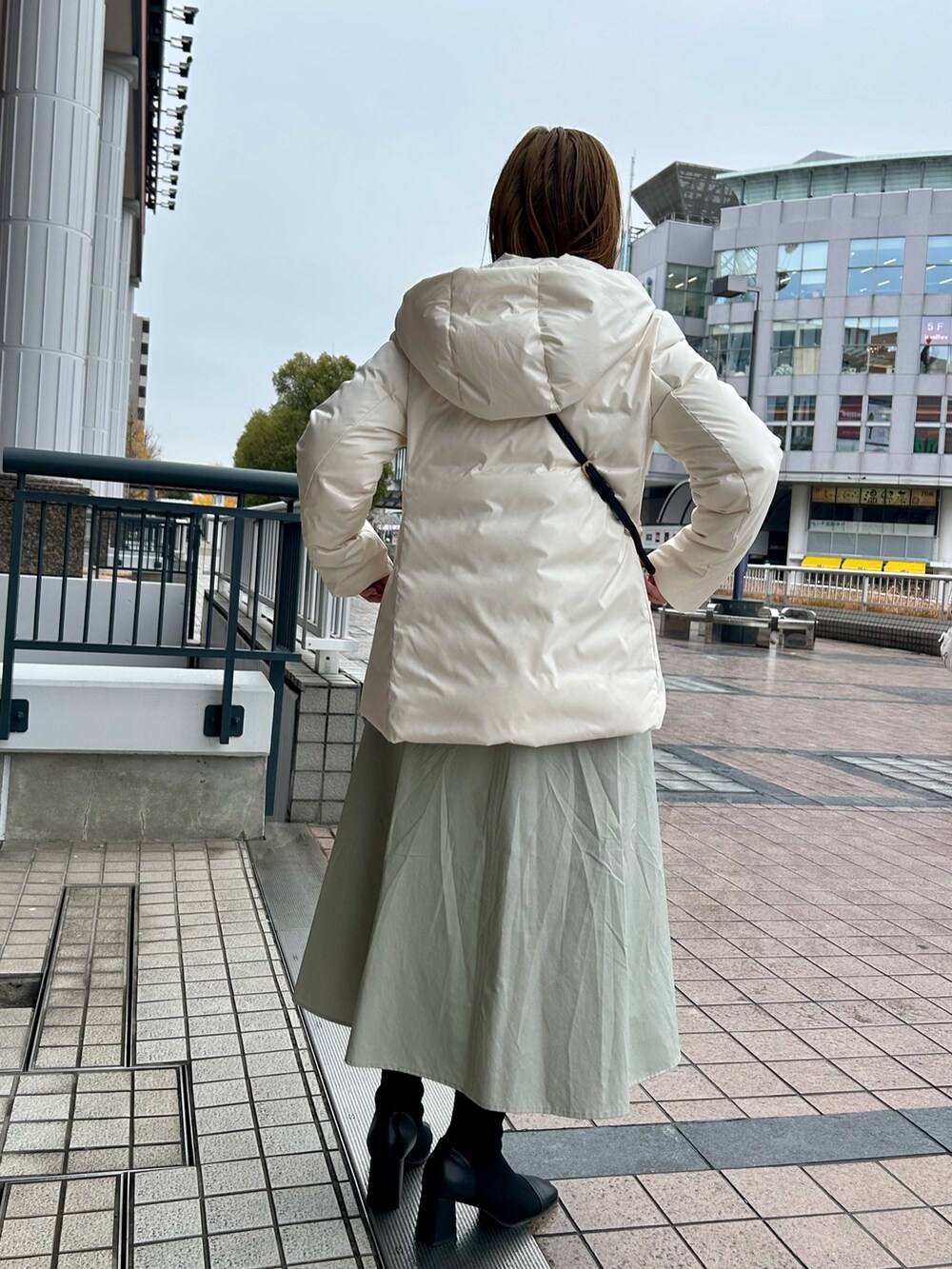 ホワイト系のダウンジャケット/コート、グレー系のワンピース、シルバー系のニット/セーターを着用したレディースの冬コーディネートの4枚目の写真