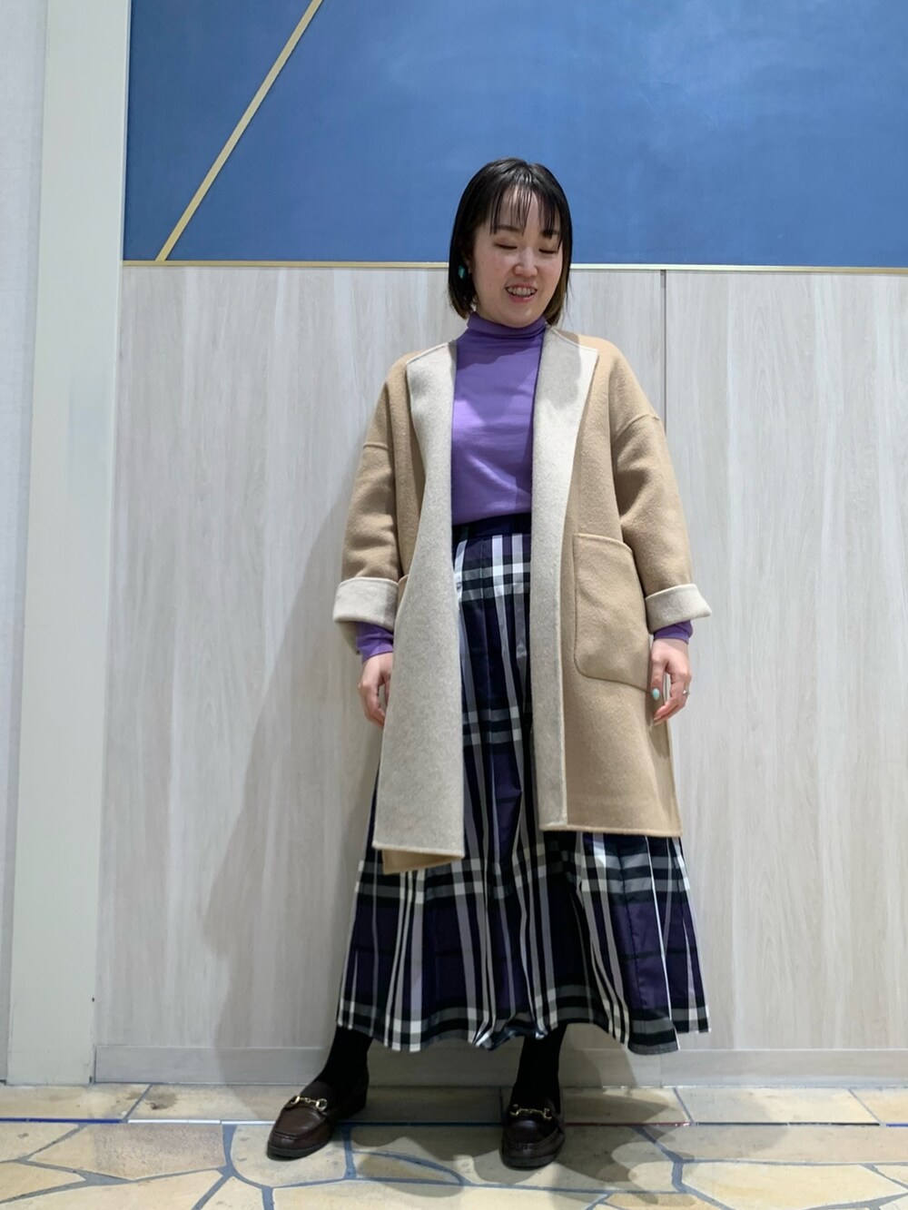 ベージュ系のその他アウター、パープル系のニット/セーター、ブルー系のスカートを着用したレディースの冬コーディネートの2枚目の写真