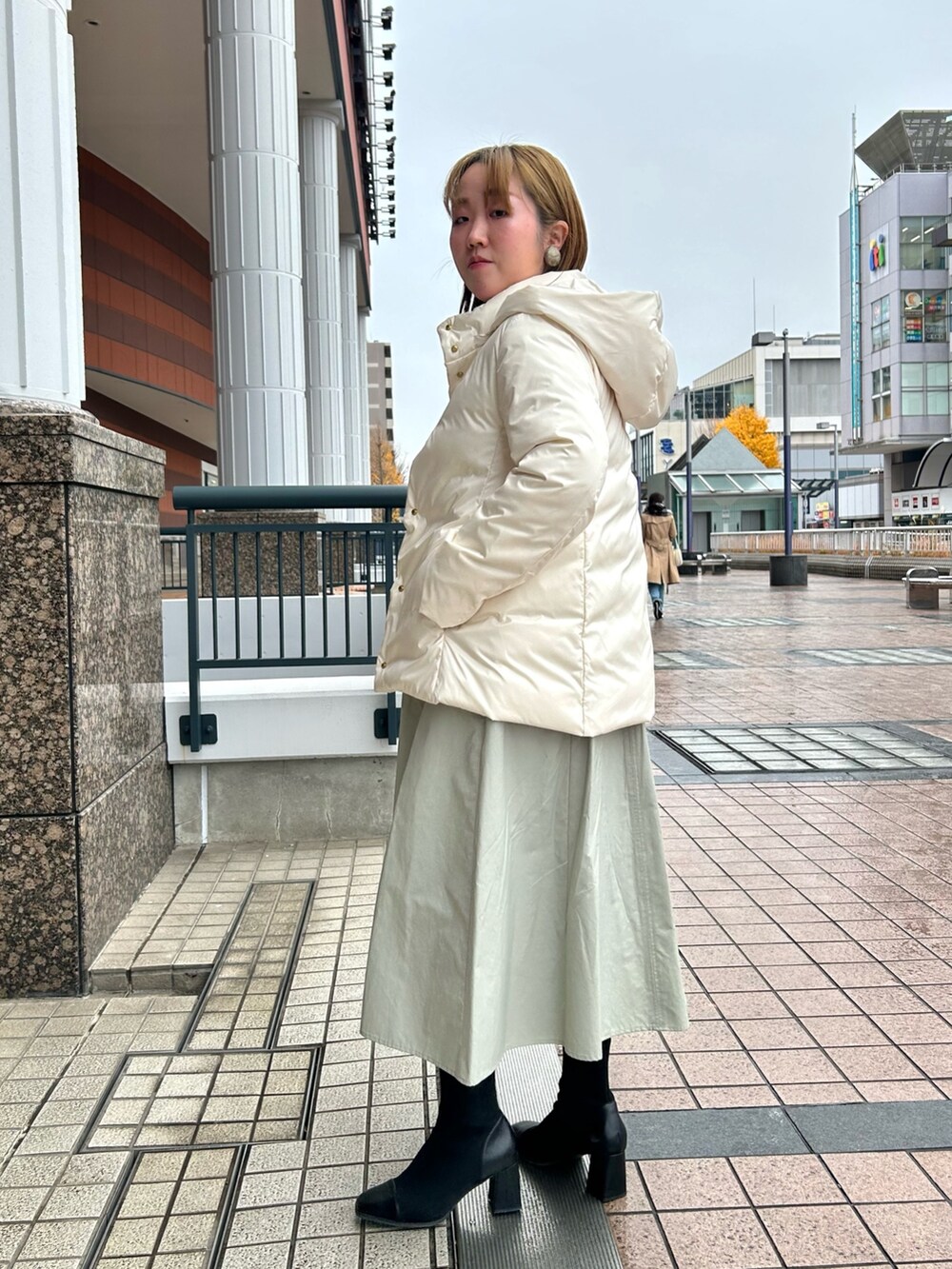 ホワイト系のダウンジャケット/コート、グレー系のワンピース、シルバー系のニット/セーターを着用したレディースの冬コーディネートの3枚目の写真