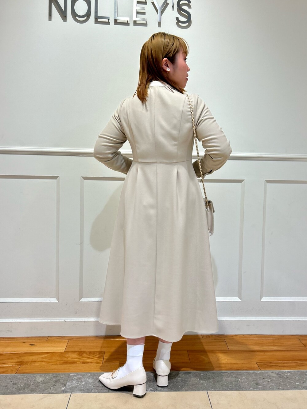 ベージュ系のワンピース、ホワイト系のショルダーバッグ、ホワイト系のイヤリングを着用したレディースの冬コーディネートの4枚目の写真