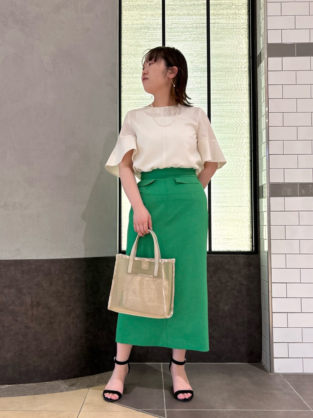 ベージュ系のトートバッグ、ホワイト系のシャツ/ブラウス、グリーン系のスカートを着用したレディースの春コーディネートの7枚目の写真