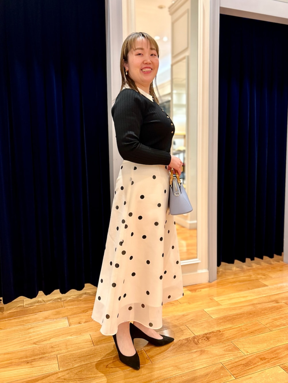 ブラック系のニット/セーター、ホワイト系のスカート、ブルー系のショルダーバッグを着用したレディースの冬コーディネートの5枚目の写真