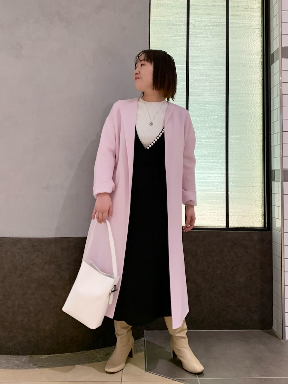 ブラック系のワンピース、ホワイト系のニット/セーター、ホワイト系のトートバッグを着用したレディースの冬コーディネートの6枚目の写真