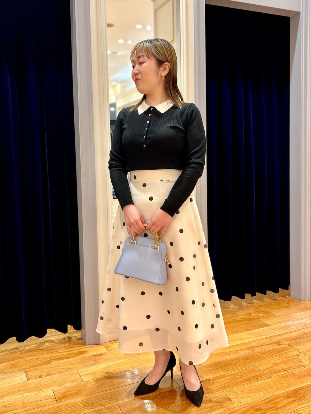ブラック系のニット/セーター、ホワイト系のスカート、ブルー系のショルダーバッグを着用したレディースの冬コーディネートの8枚目の写真