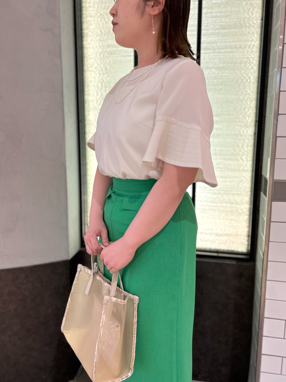 ベージュ系のトートバッグ、ホワイト系のシャツ/ブラウス、グリーン系のスカートを着用したレディースの春コーディネートの10枚目の写真