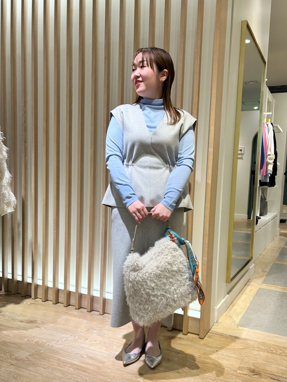 グレー系のベスト、グレー系のスカート、ブルー系のニット/セーターを着用したレディースの冬コーディネートの5枚目の写真