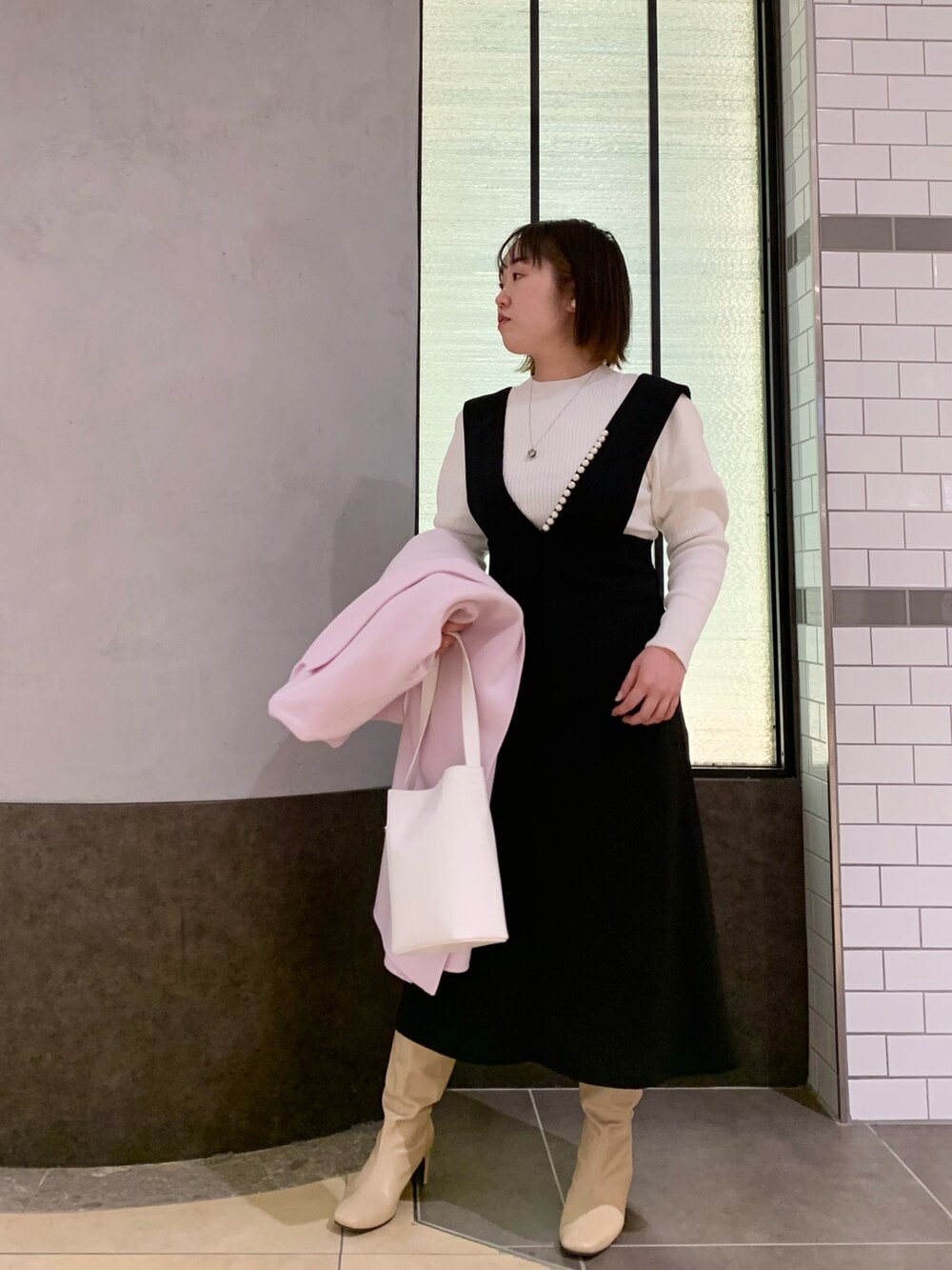 ブラック系のワンピース、ホワイト系のニット/セーター、ホワイト系のトートバッグを着用したレディースの冬コーディネートの8枚目の写真