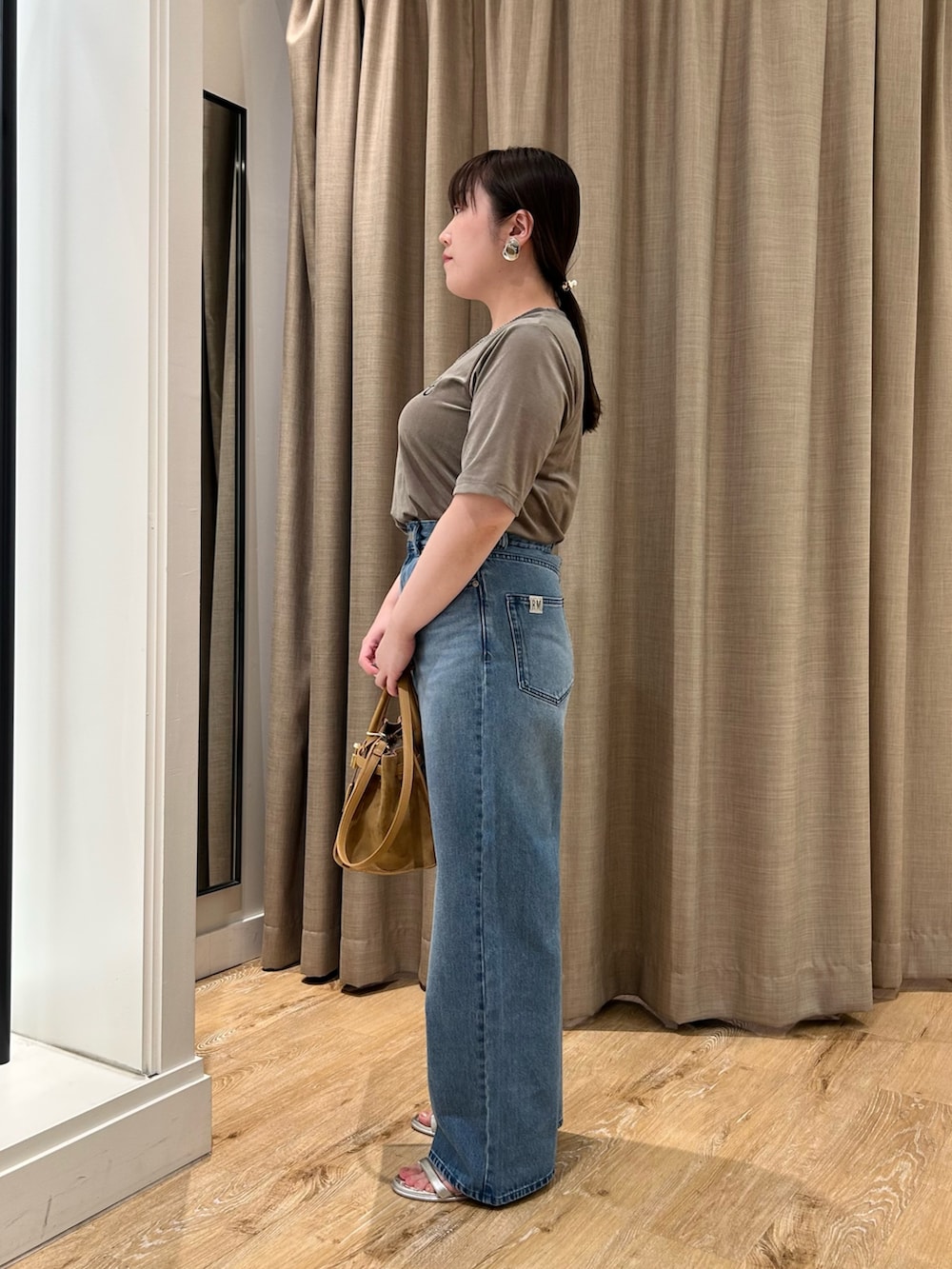 グリーン系のTシャツ/カットソー、ブルー系のデニムパンツ、イエロー系のトートバッグを着用したレディースの秋コーディネートの2枚目の写真