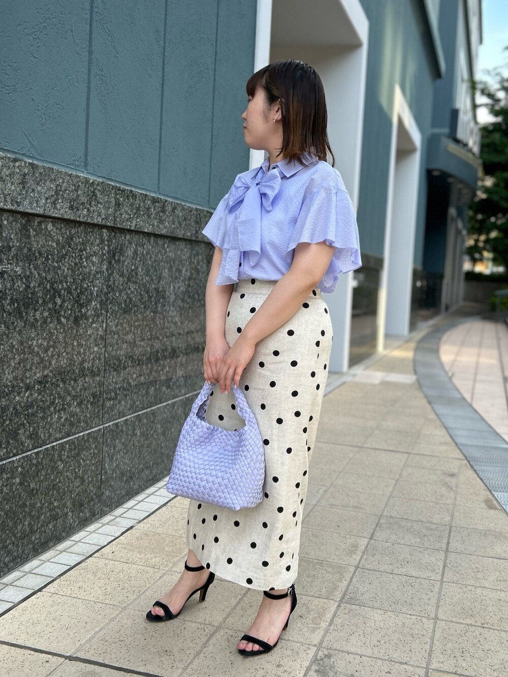パープル系のシャツ/ブラウス、ベージュ系のスカート、パープル系のショルダーバッグを着用したレディースの春コーディネートの3枚目の写真
