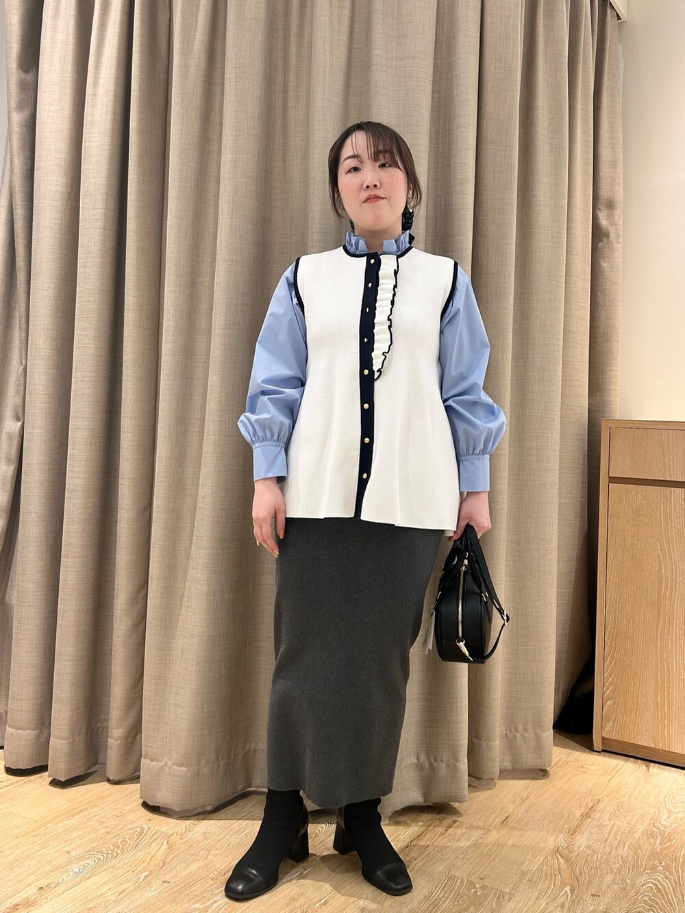 ホワイト系のベスト、ブルー系のシャツ/ブラウス、グレー系のスカートを着用したレディースの冬コーディネートの5枚目の写真