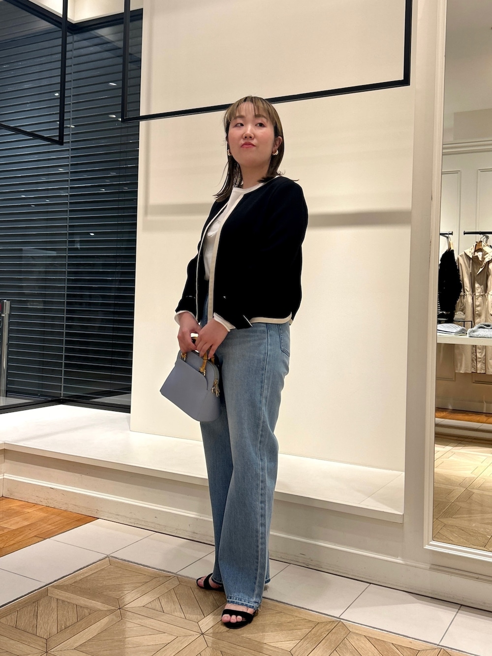 ブラック系のノーカラージャケット、ホワイト系のTシャツ/カットソー、ブルー系のデニムパンツを着用したレディースの冬コーディネートの7枚目の写真