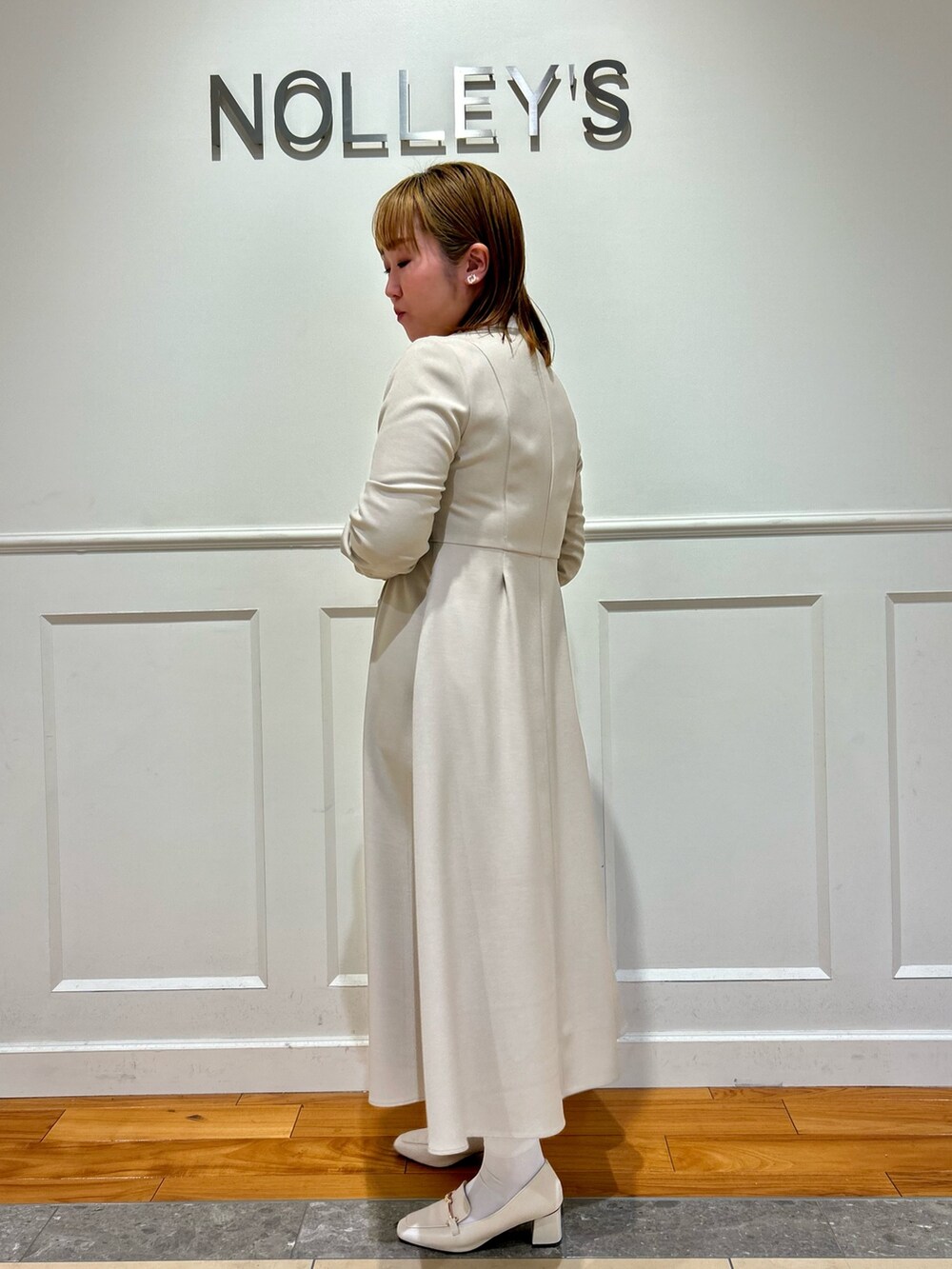 ベージュ系のワンピース、ホワイト系のショルダーバッグ、ホワイト系のイヤリングを着用したレディースの冬コーディネートの3枚目の写真