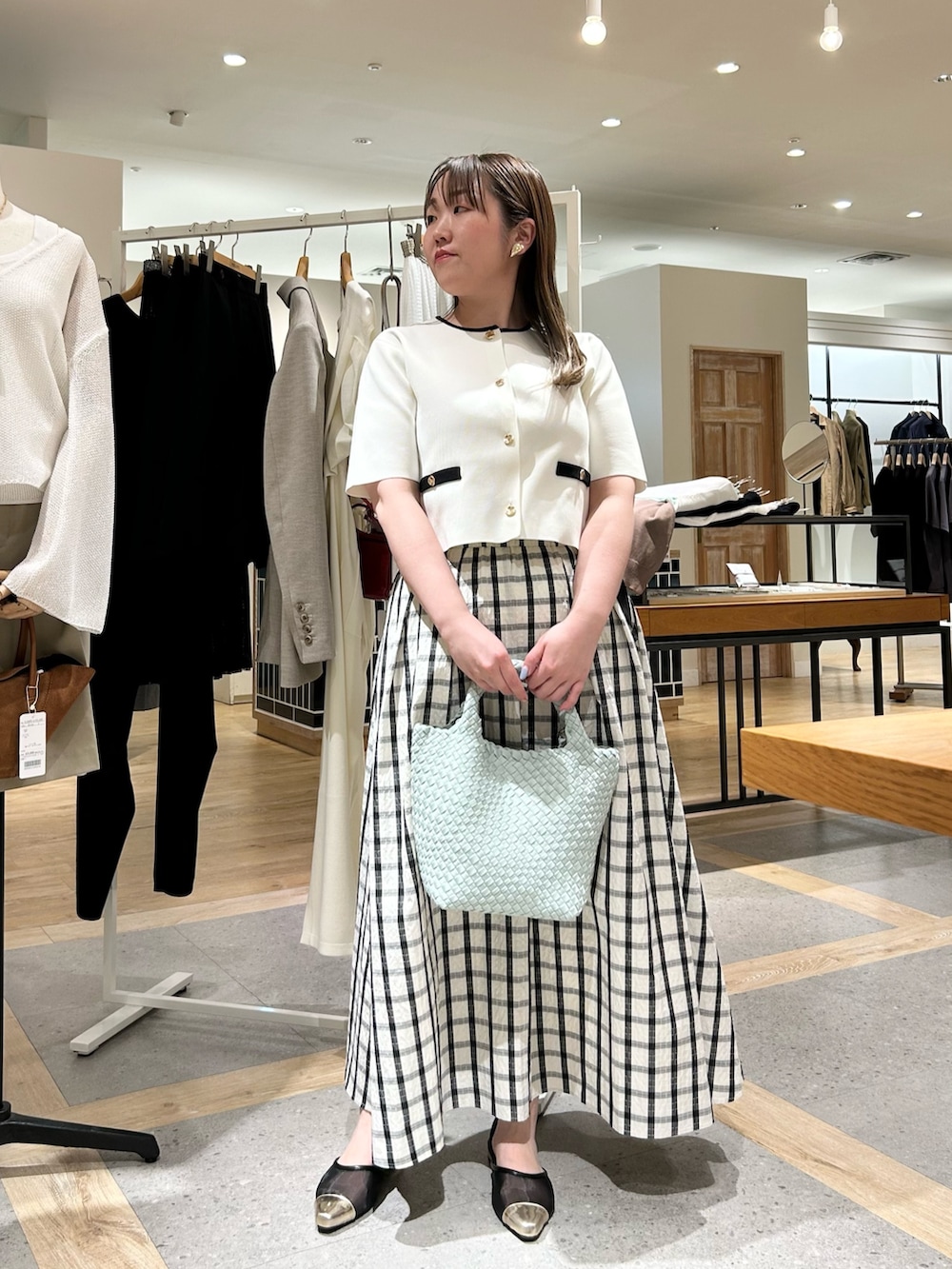 ホワイト系のノーカラージャケット、グリーン系のショルダーバッグ、ゴールド系のイヤリングを着用したレディースの夏コーディネートの6枚目の写真