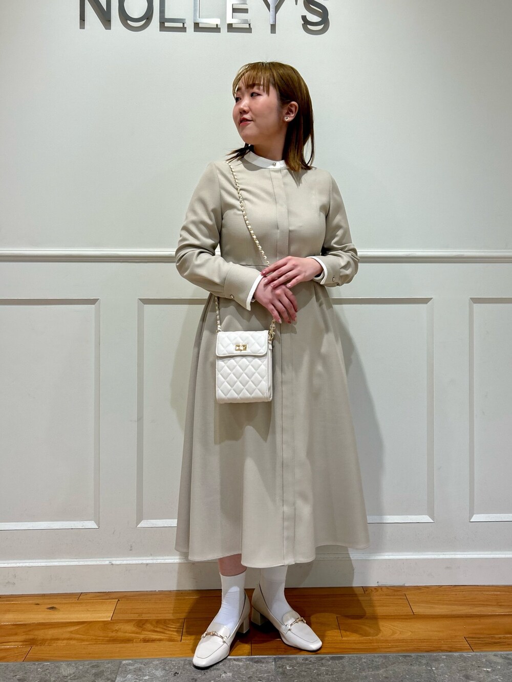 ベージュ系のワンピース、ホワイト系のショルダーバッグ、ホワイト系のイヤリングを着用したレディースの冬コーディネートの8枚目の写真