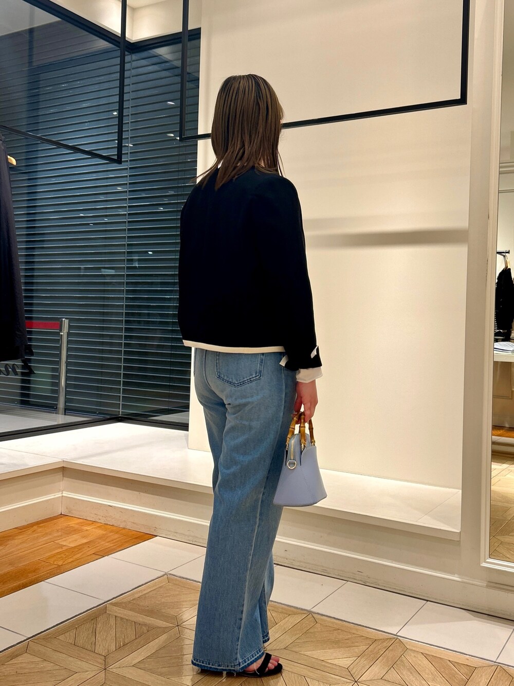 ブラック系のノーカラージャケット、ホワイト系のTシャツ/カットソー、ブルー系のデニムパンツを着用したレディースの冬コーディネートの4枚目の写真