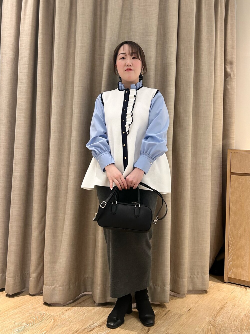 ホワイト系のベスト、ブルー系のシャツ/ブラウス、グレー系のスカートを着用したレディースの冬コーディネートの9枚目の写真